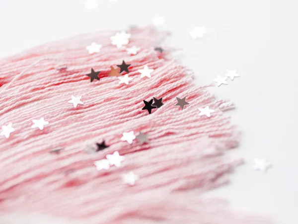 Cera rosa e cauda de unicórnio bonito feito de fios. Brinquedo feito à mão de malha no fundo branco com estrelas de prata confetti. Criatura na moda, símbolo da magia e milagres . — Fotografia de Stock