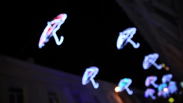 Decorazione esterna a forma di ombrelli. Carino lampadine colorate brillano al buio. sfondo sfocato e sfocato. Yalta, Crimea . — Video Stock