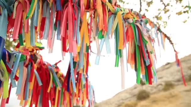 Vícebarevné tkaniny se pohupuje ve větru. Starověká tradice svázání stuh na větvích stromů, aby přilákaly hodně štěstí a naplálo touhy. Krymu. — Stock video