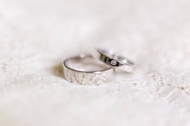 Beyaz dantel arka plan üzerinde elmas ile Altın alyans. Düğün detayları. Geleneksel aksesuar, aşk ve evlilik sembolü.