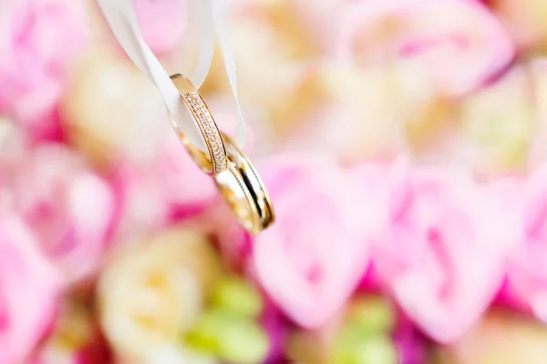 Anéis de casamento dourados em buquê de noiva com rosas rosa e amarela. Composição floral tradicional para cerimônia de casamento. Símbolo romântico de amor e casamento . — Fotografia de Stock