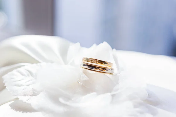 Золотые обручальные кольца с бриллиантами на белой шелковой ткани. Традиционный символ любви и брака . — стоковое фото