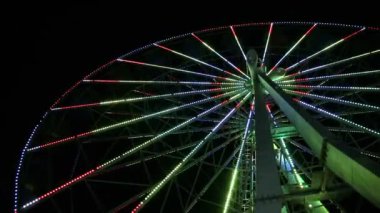Renkli yanıp sönen ışıklarla dekore edilmiş Şehir Dönme Dolap. Karanlık çöktükten sonra dönen dairesel sürüşışık gösterisi. Kırım.