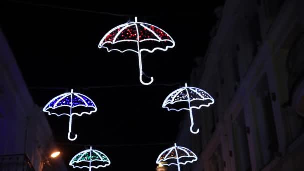 Decoración exterior en forma de paraguas. Lindas bombillas de colores brillan en la oscuridad. Yalta, la Crimea . — Vídeo de stock