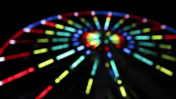 Kolečko City Ferris zdobené barevným blikajícím světlem. Světelná show na otáčející se kruhové jízdě po setmění. Zaostřený, rozmazaný. Krymu. — Stock video