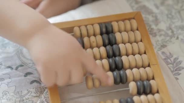 Toddler počítá s dřevěnou Abacus. Baby si hraje se starým dřevěným zařízením. Dítě se učí počítat. — Stock video