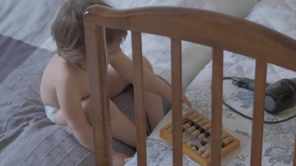 Toddler is counting with wooden abacus. Baby is playing with old wooden device. Child is learning to count. — Stock Video