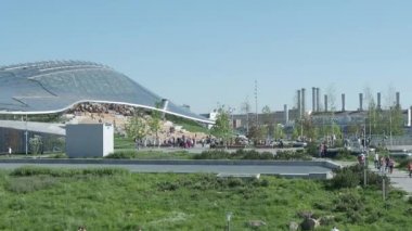 Moskova, Rusya - 18 Mayıs 2019. Kızıl Meydan yakınlarındaki Zaryadye peyzaj kentsel park. Çimler ve çiçek tarhları arasında yürüyen insanlar. Amfitiyatrolu konser salonunun cam kubbesi.