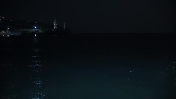 Világítótorony a krími Jalta kikötőjében. Piros fény villog éjszaka. Fekete-tenger. — Stock videók