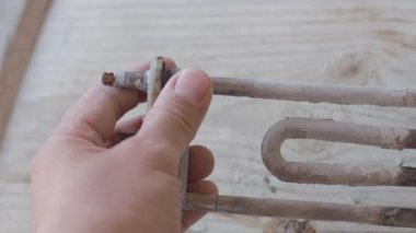 Çamaşır makinesinden yanmış ısıtma elemanı. Adam kireç ile kaplı türbülans elektrikli ısıtma elemanı dokunuyor.