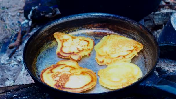 Touristen backen Pfannkuchen in der Pfanne über dem Feuer. Lagerfeuer im Wald. — Stockvideo