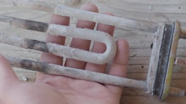 Çamaşır makinesinden yanmış ısıtma elemanı. Adam kireç ile kaplı türbülans elektrikli ısıtma elemanı dokunuyor.