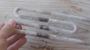Çamaşır makinesinden yanmış ısıtma elemanı. Adam kireç ile kaplı türbülans elektrikli ısıtma elemanı dokunuyor.