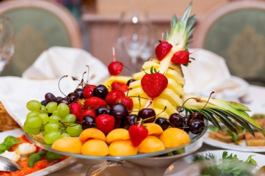 Çilek, üzüm, kayısı, tatlı kiraz, ananas - Meyve tabağı ile ziyafet için servis edilen tablo.