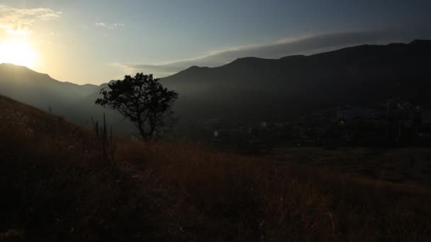 Puesta de sol brumosa en la fortaleza Sudak. Fondo natural de otoño con hierba seca, montañas y luz solar. Crimea . — Vídeos de Stock