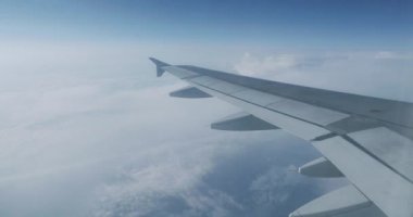 Uçağın penceresinden mavi gökyüzü ve kabarık beyaz bulutlar görünümü. Uçan uçaktan manzara.