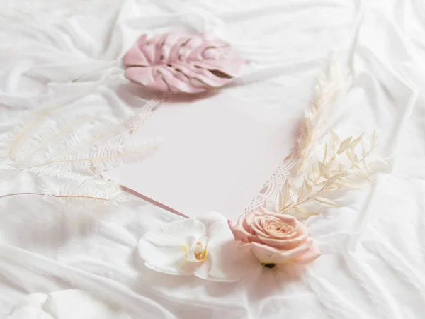 Phalaenopsis Orchid, Cortaderia selloana (pampas grass) and pink Monstera leaf on white fabric. Graceful background with copy space invitation and flowers on folded textile. Cozy still life backdrop. — Stock Photo, Image