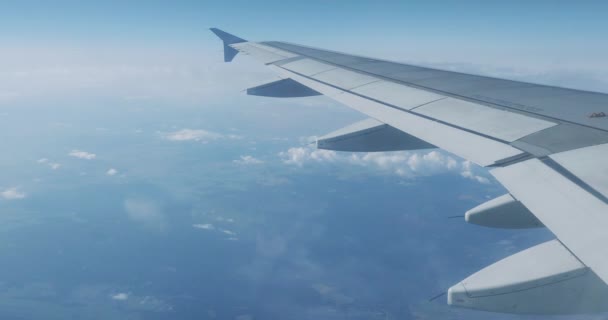 Vista sobre el cielo azul y nubes blancas esponjosas a través de la ventana del avión. Vista panorámica desde el avión volador . — Vídeos de Stock
