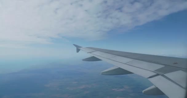 Vista sobre el cielo azul y nubes blancas esponjosas a través de la ventana del avión. Vista panorámica desde el avión volador . — Vídeos de Stock