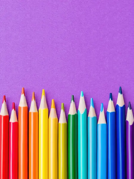 Rząd kolorowych ołówków akwarelowych na tle bzu. Materiały szkolne na fioletowym tle papieru. Papeteria dziecięca. Powrót do szkoły purpurowe tło. — Zdjęcie stockowe