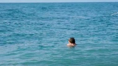 Oğlu denizde yüzen baba. Yeni yürümeye başlayan adam su dalgalarında oynuyor. Aile eğlence aktivitesi.