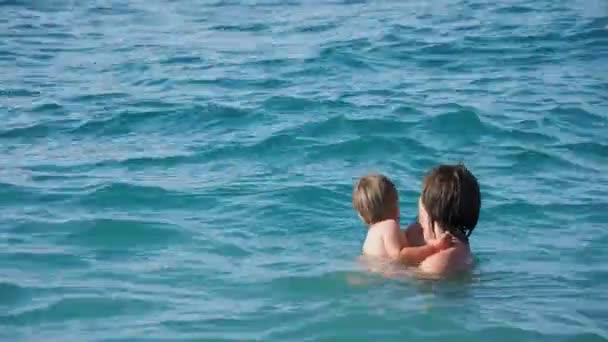 Padre con figlio che nuota in mare. Un uomo con un bambino sta giocando sulle onde dell'acqua. Attività ricreative in famiglia . — Video Stock