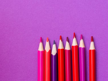 Mor kağıt arka plan üzerinde kırmızı ve macenta kalemler dikey satır. Okul malzemeleri. Leylak kopyalama alanı olan çocuk kırtasiye. Okula geri dön pembe fon.