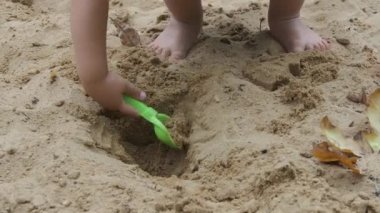 Toddler çocuk kum ve kalıpları ile kum havuzunda oynuyor. Bebek çocuk oyun alanında çıplak ayakla yürür. Açık hava eğlence aktivitesi,.