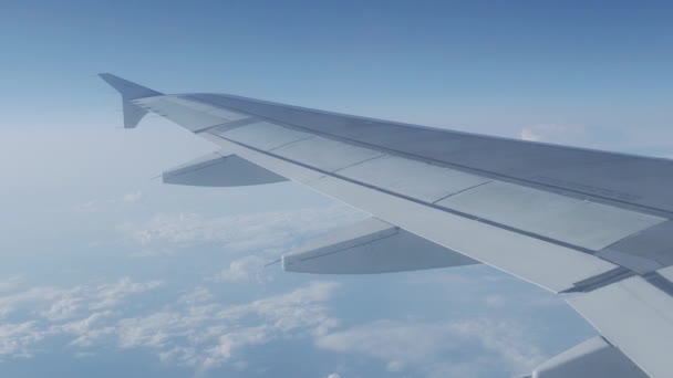 Vista sobre el cielo azul y nubes blancas esponjosas a través de la ventana del avión. Vista panorámica desde el avión volador . — Vídeos de Stock