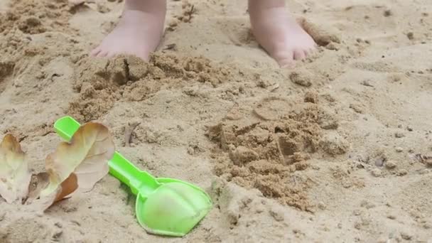 Menino está brincando com areia e moldes em caixa de areia. Caminhadas de bebê com os pés descalços no parque infantil. Atividades de lazer ao ar livre ,. — Vídeo de Stock