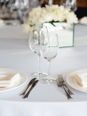 Sofra ziyafet için çatal bıçak, şarap bardağı ve peçeteyle servis edildi. Pastel renkli dekorasyonlar.