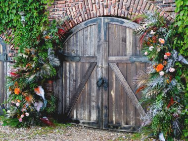 Düğün töreni için geleneksel kemer olarak eski ahşap kapılar. Eğrelti otu, palmiye ağacı yaprakları ve sarmaşık ile dekorlar. Düğün açık havada kurmak.