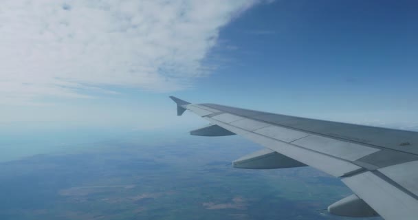 Pohled na modrou oblohu a načechrané bílé mraky skrz okno letadla. Vyhlídkové zobrazení z letounu. — Stock video