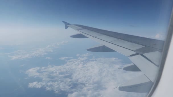 Blick auf blauen Himmel und flauschig weiße Wolken durch das Fenster des Flugzeugs. Aussichtsreiche Aussicht aus dem Flugzeug. — Stockvideo