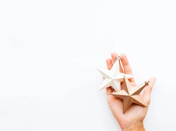 La mujer lleva a cabo la decoración de Año Nuevo - dos estrellas sobre fondo blanco. Vista superior de la decoración para el árbol de Navidad . —  Fotos de Stock