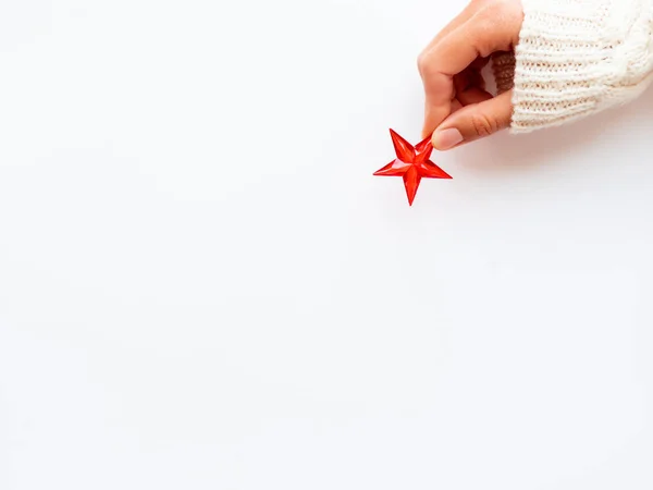 La mujer en el jersey de punto tiene la decoración de Año Nuevo - la estrella roja sobre el fondo blanco. Vista superior de la decoración para el árbol de Navidad . —  Fotos de Stock