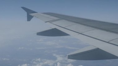 Uçağın penceresinden mavi gökyüzü ve kabarık beyaz bulutlar görünümü. Uçan uçaktan manzara.