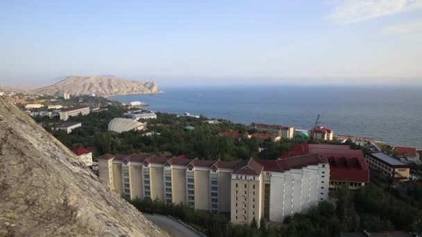 Aerial view on Sudak town from Sudak fortress. Roofs of buildings and Black sea. Crimea. — Stock Video