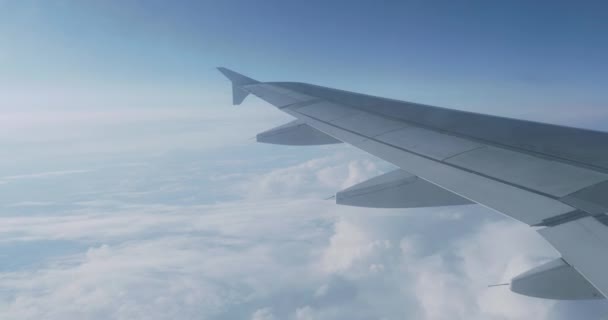 Vista sobre el cielo azul y nubes blancas esponjosas a través de la ventana del avión. Vista panorámica desde el avión volador . — Vídeos de Stock