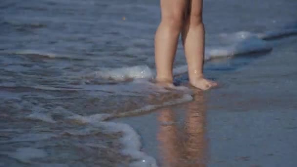 Niño pequeño en traje de baño está jugando con arena en el lado del mar . — Vídeos de Stock