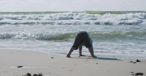 Kleinkind in Weste spielt mit Sand am Meer. — Stockvideo