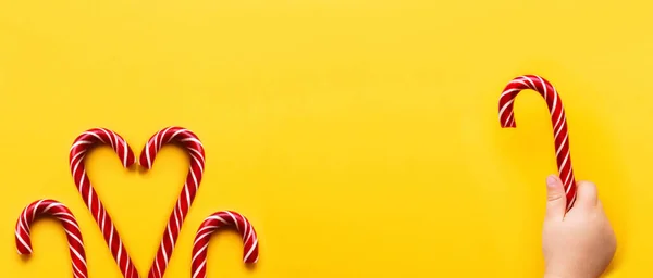 Coração feito de dois cones de doces de Natal no fundo amarelo. Doces coloridos de férias com espaço de cópia brilhante. Sobremesa tradicional wtih listras vermelhas e brancas . — Fotografia de Stock