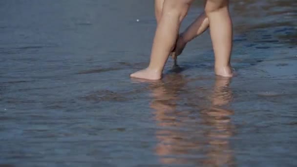 Niño pequeño en traje de baño está jugando con arena en el lado del mar . — Vídeos de Stock