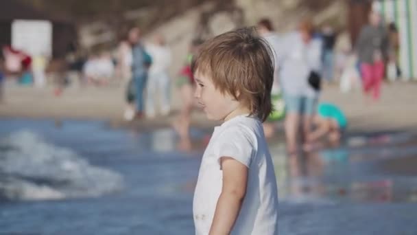 Niño pequeño en traje de baño está jugando con arena en el lado del mar . — Vídeos de Stock