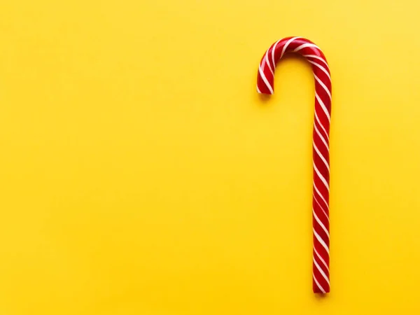 Cone de doces de Natal no fundo amarelo. Férias coloridas doce com espaço de cópia brilhante. Sobremesa tradicional wtih listras vermelhas e brancas . — Fotografia de Stock