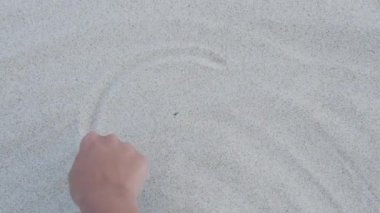 Kadın Dünya gezegenini kumun üzerine çiziyor. Gezegenimizin sahildeki sembolü. Çevre koruma kavramı.
