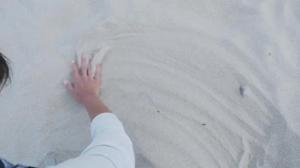 女性は砂の上に心を描いている。ビーチでの愛とロマンスのシンボル. — ストック動画