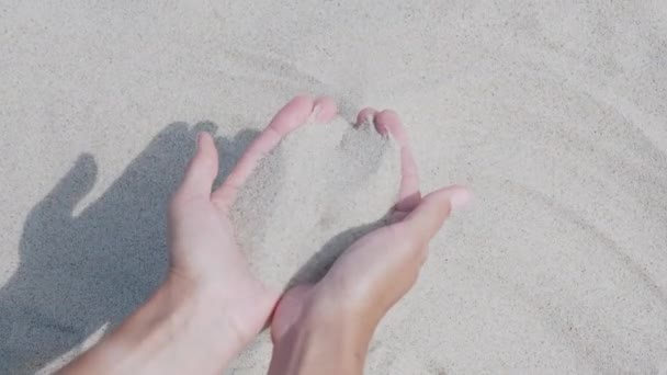 Sand ergießt sich durch Finger. Frau spielt mit Sand am Strand. Symbol der Zeit. — Stockvideo