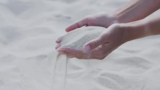 Sand ergießt sich durch Finger. Frau spielt mit Sand am Strand. Symbol der Zeit. — Stockvideo