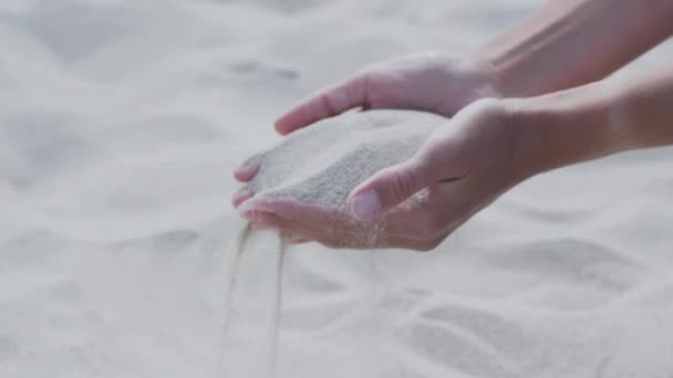 La arena vierte a través de los dedos. La mujer está jugando con arena en la playa. Símbolo del tiempo . — Vídeo de stock